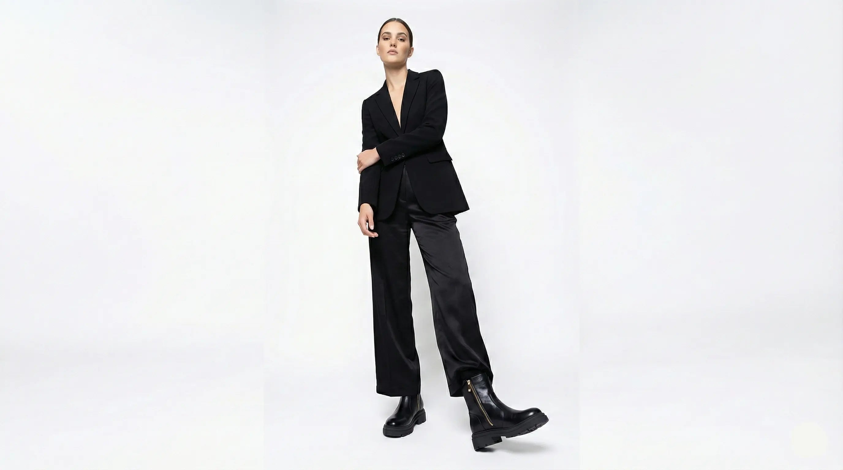 Person wearing a black suit and boots on a white background