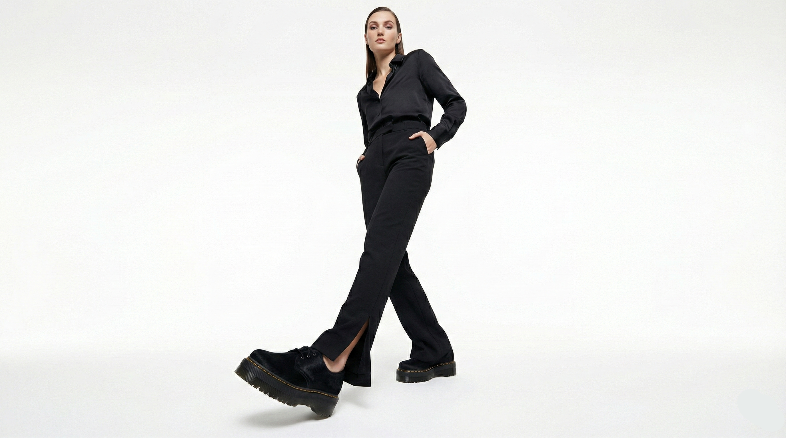 Person wearing a black outfit with black shoes on a white background