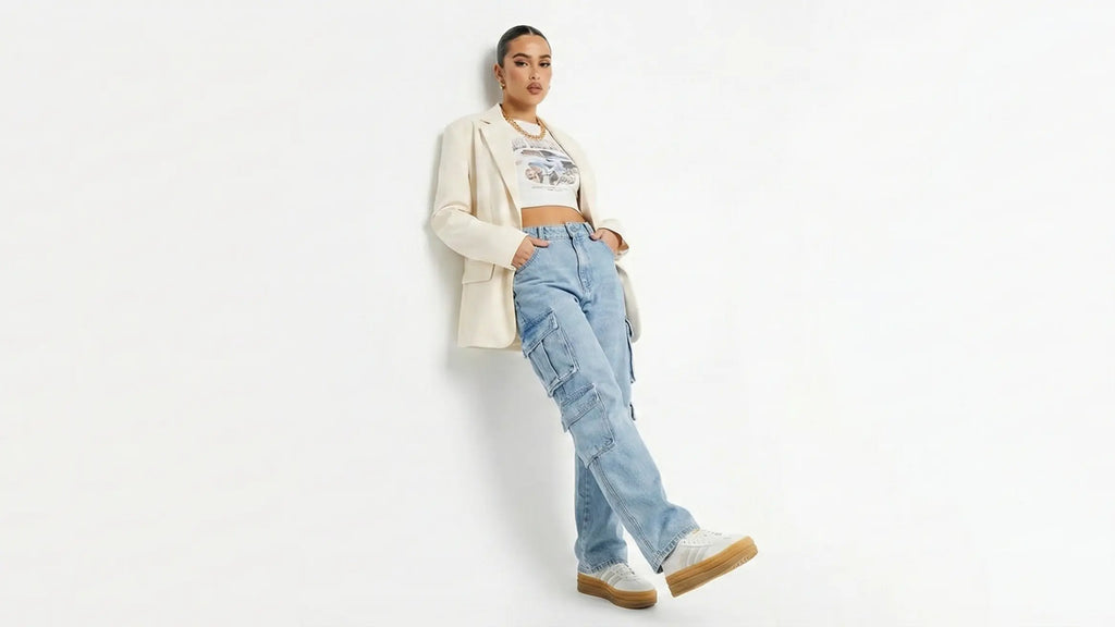 Woman wearing a white blazer, white shirt, blue jeans, and brown boots on a white background