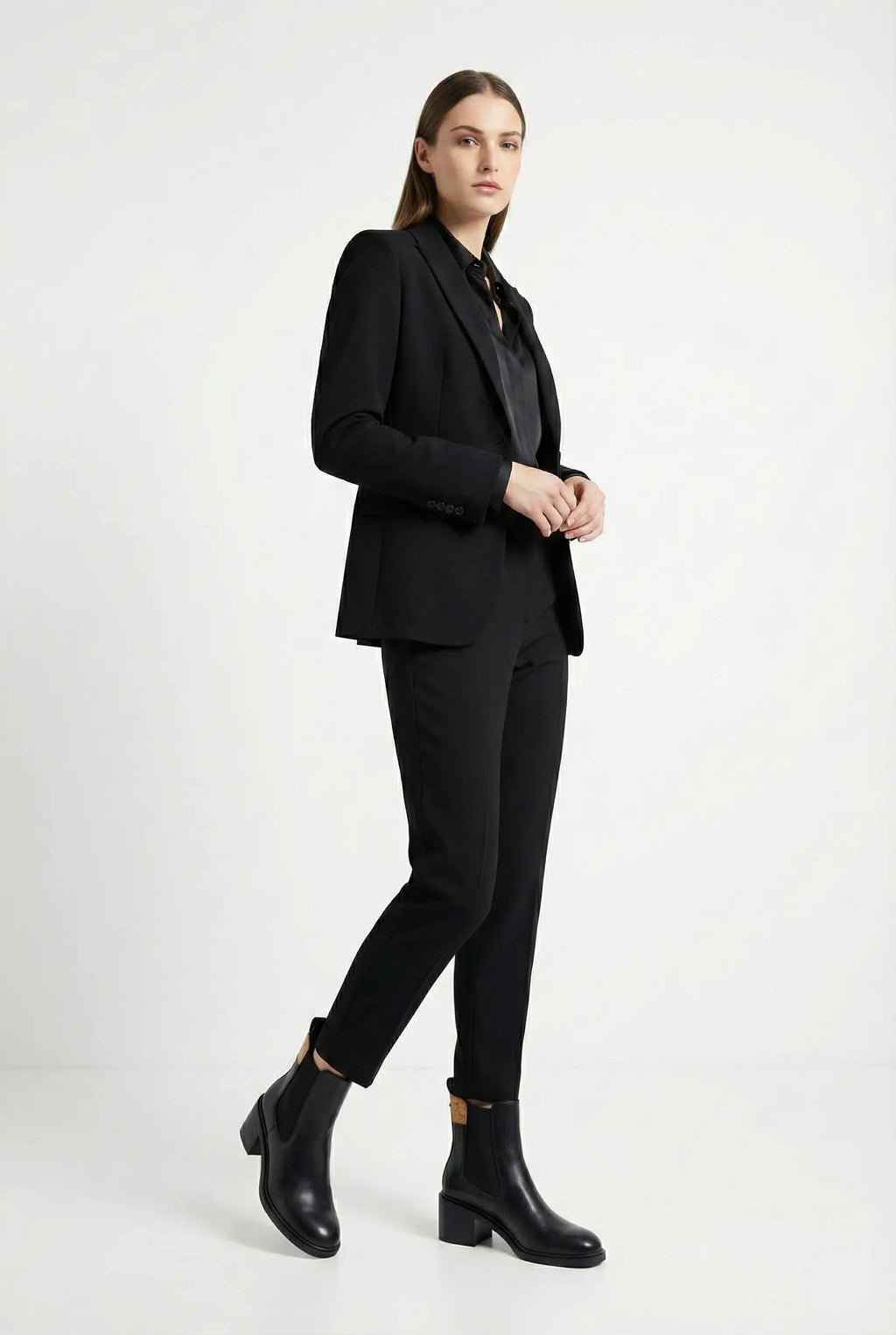 Woman wearing a black suit with black boots on a white background