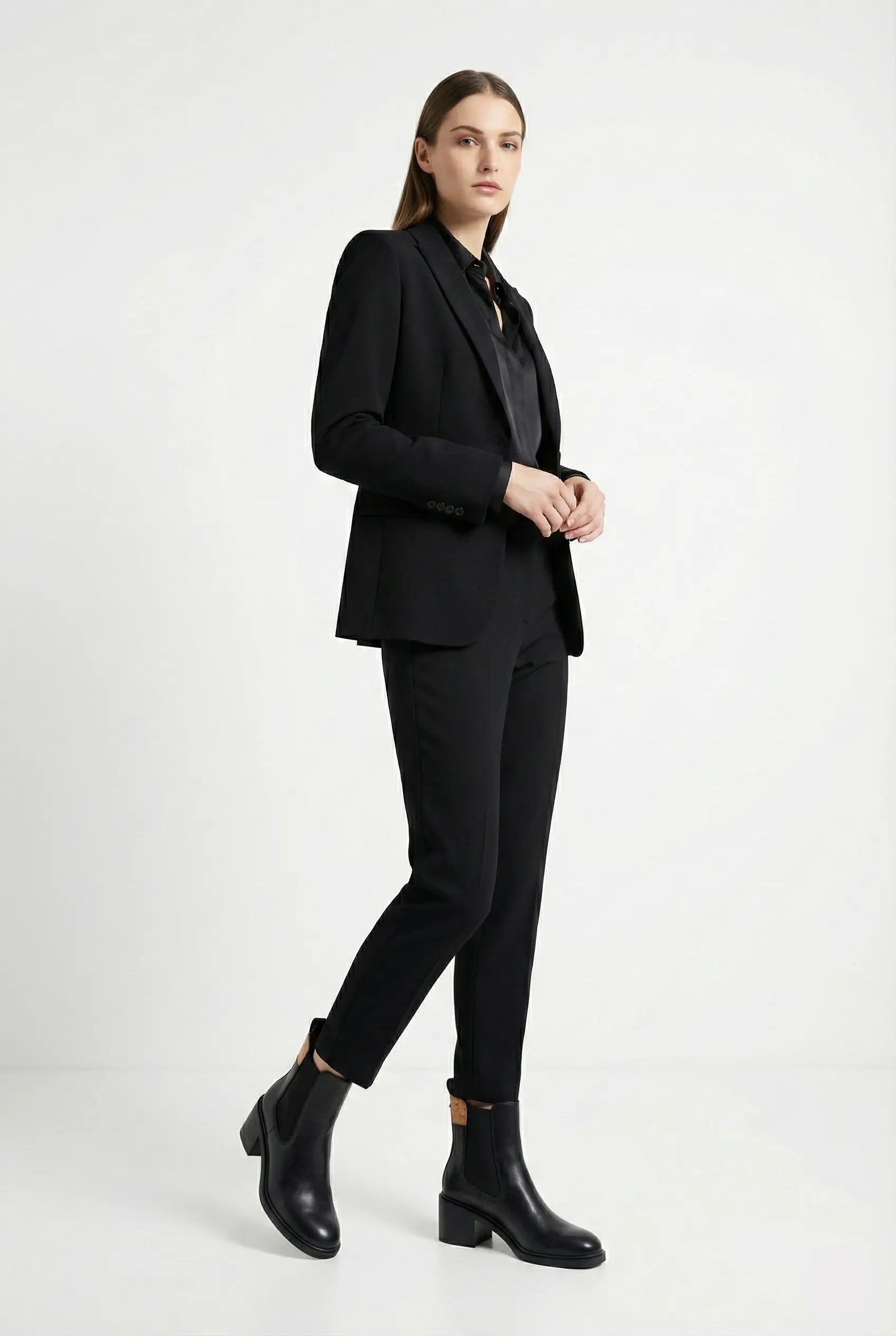 Woman wearing a black suit with black boots on a white background
