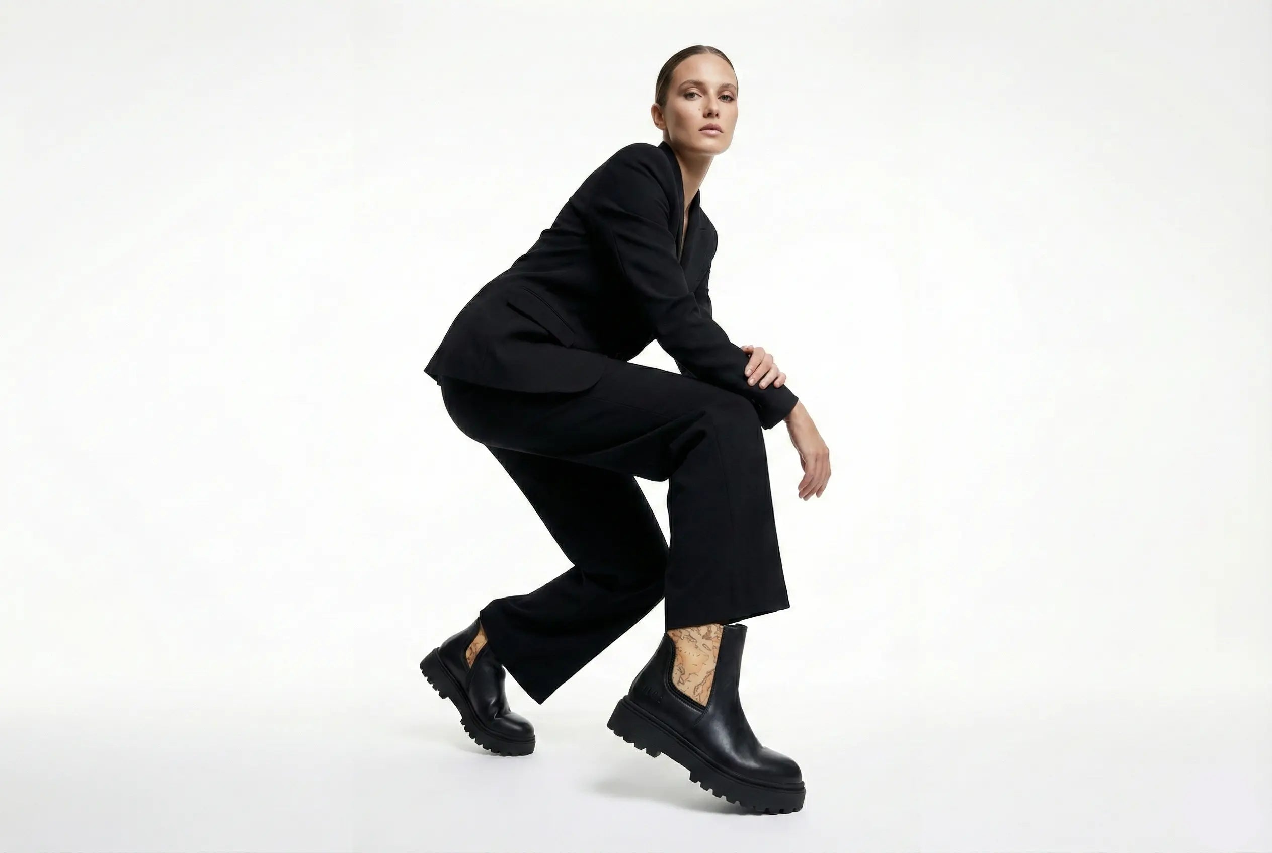 Person wearing a black outfit with black boots on a white background
