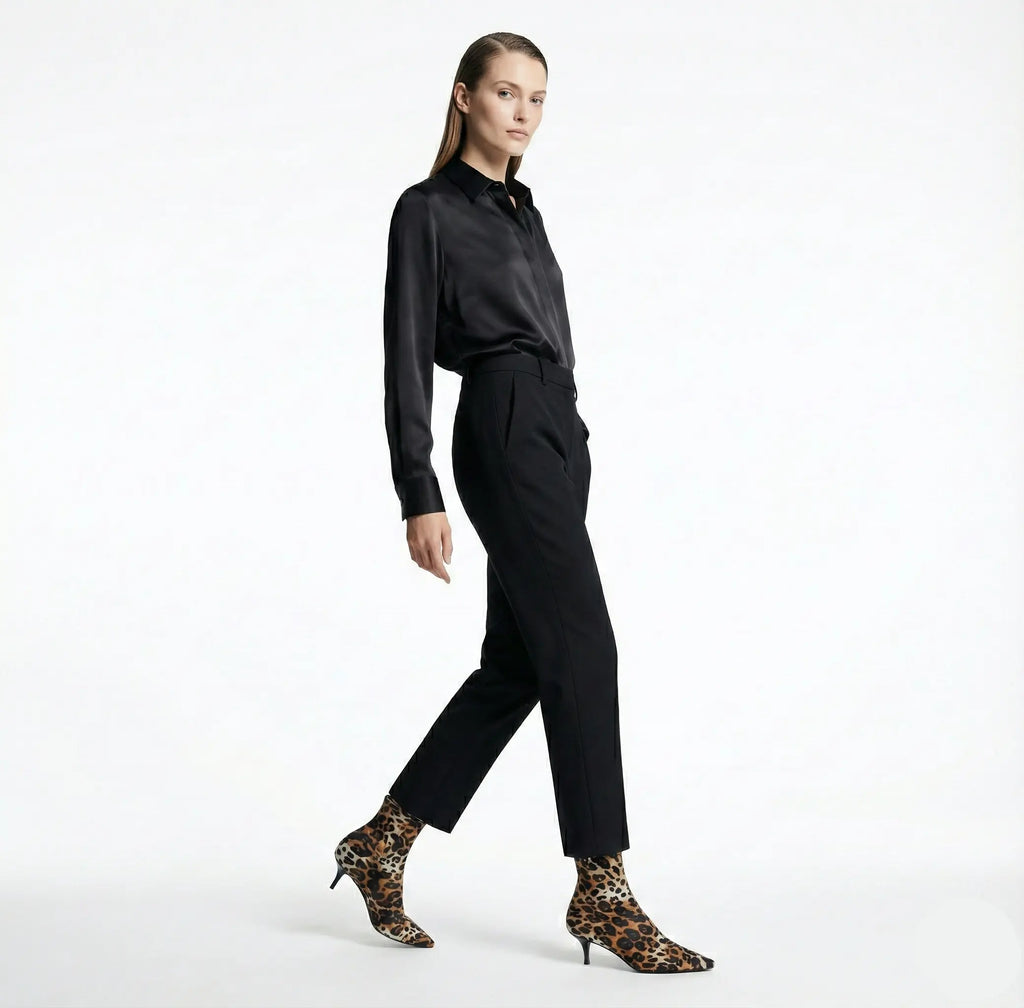 Woman wearing a black outfit with leopard print shoes on a white background