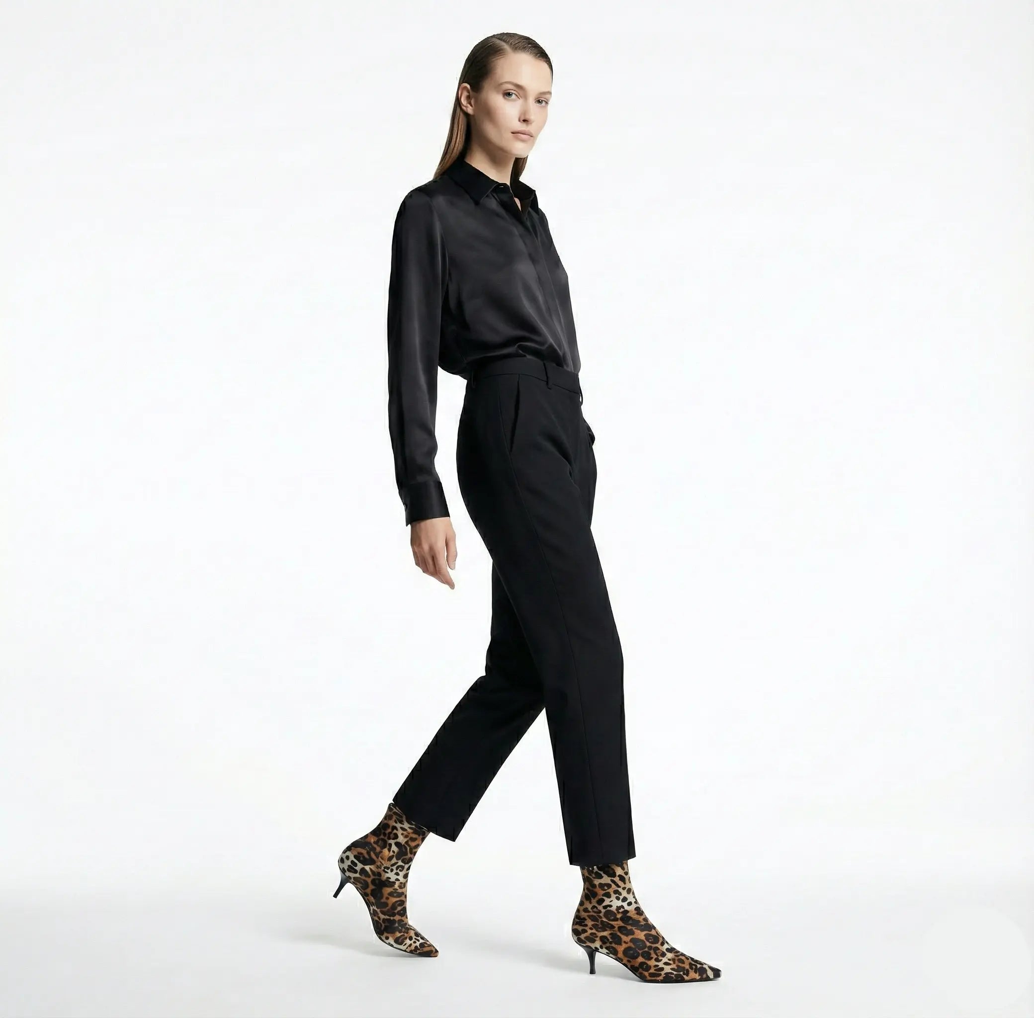 Woman wearing a black outfit with leopard print shoes on a white background