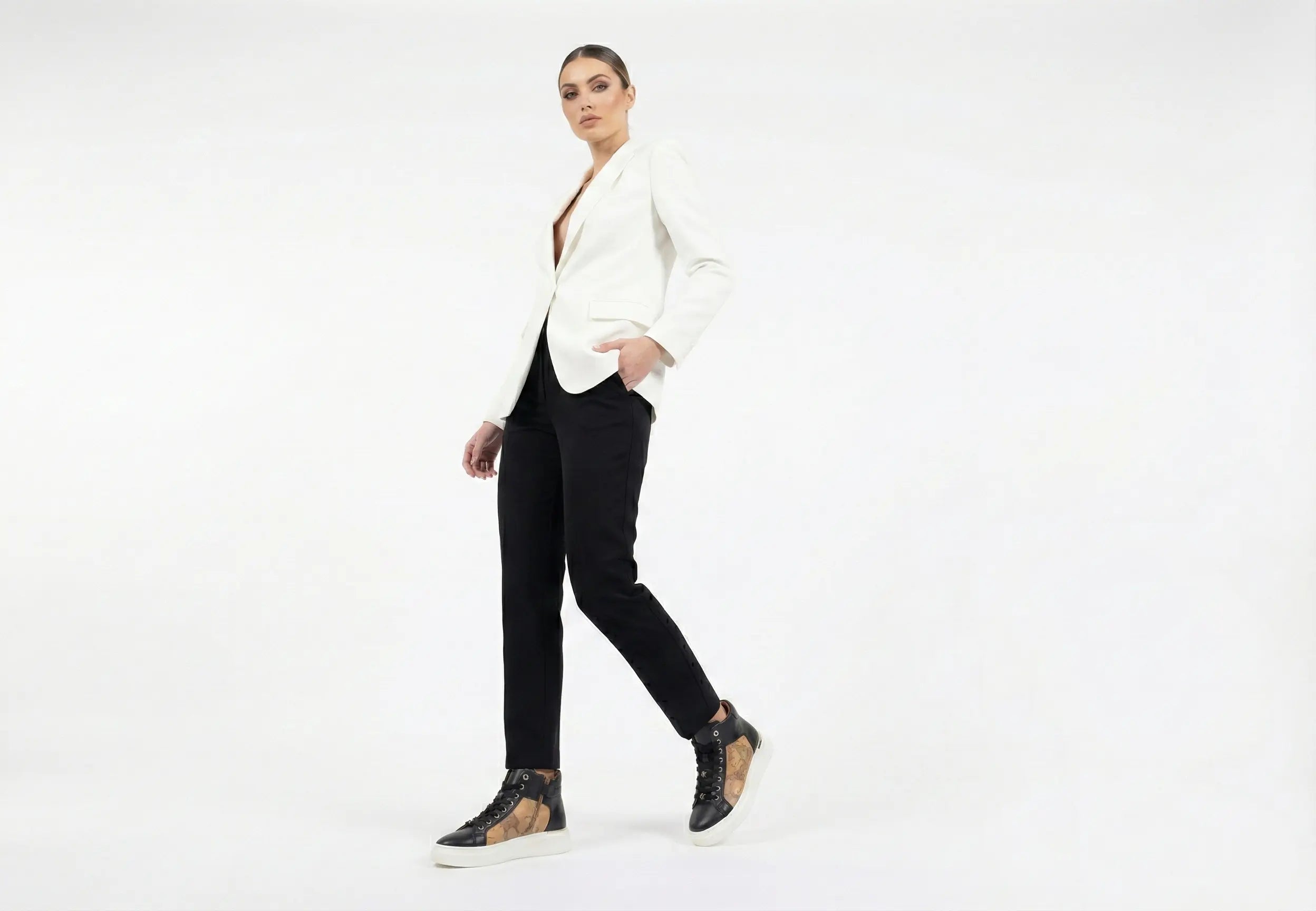 Woman wearing a white blazer and black pants on a white background