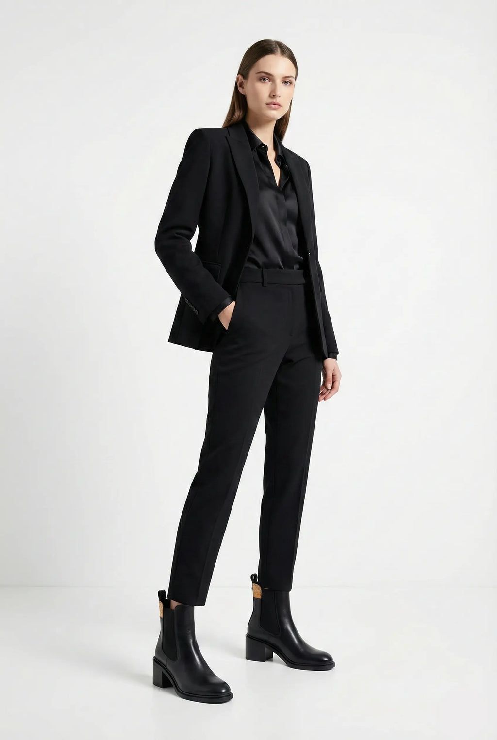 Woman wearing a black suit with black boots on a white background