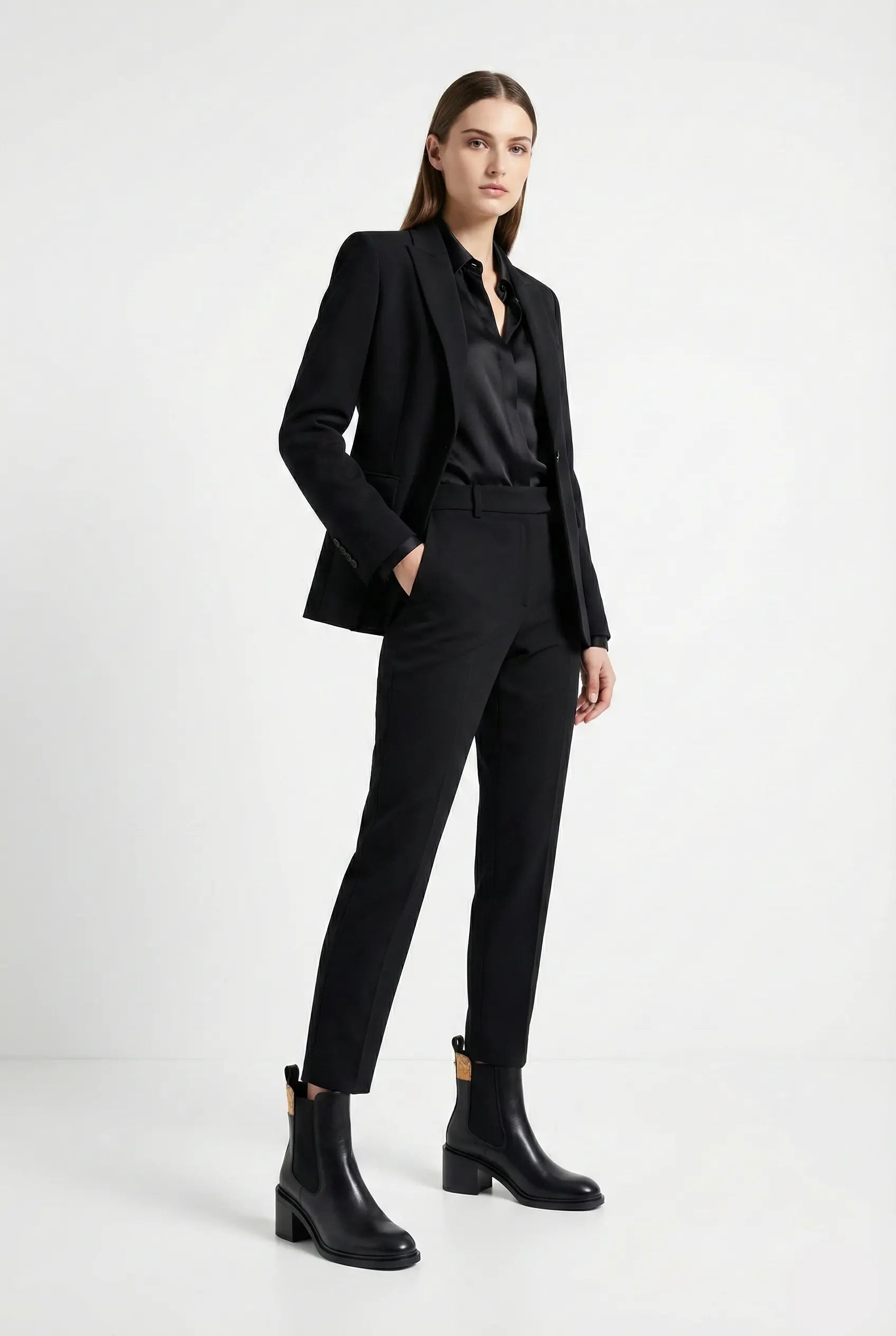 Woman wearing a black suit with black boots on a white background