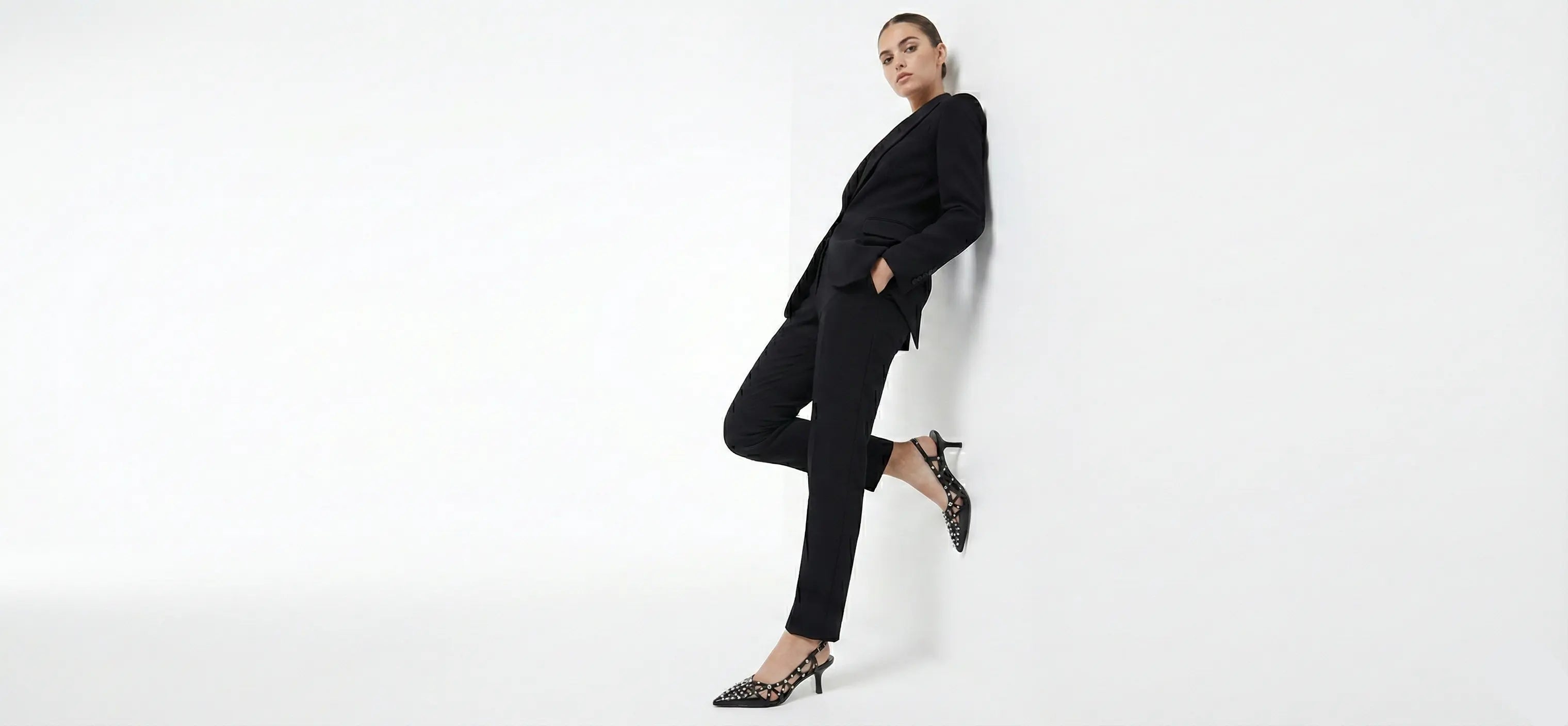 Woman in a black outfit posing against a white background