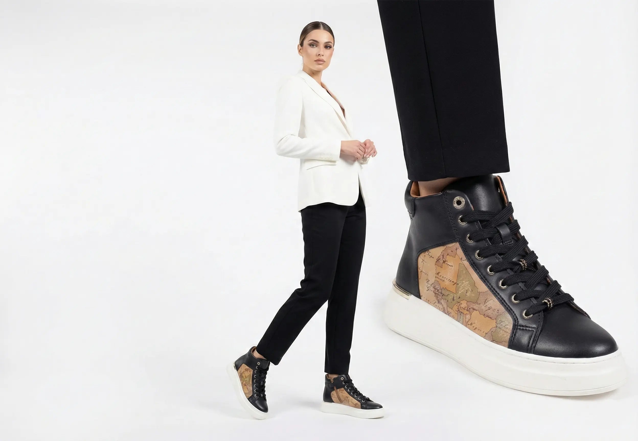 Person wearing black high-top sneakers with world map design on a white background